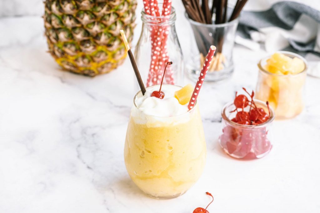 glass of Dole Whip on counter with bowl of cherries