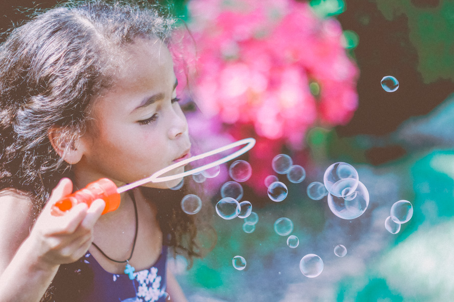 young girl blowing bubbles in a garden