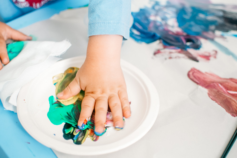 toddler hand in paint making hand prints
