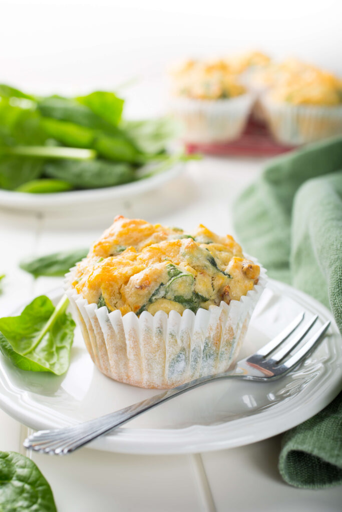 Spinach Goat Cheese and Sweet Potato Muffins on a plate with raw spinach