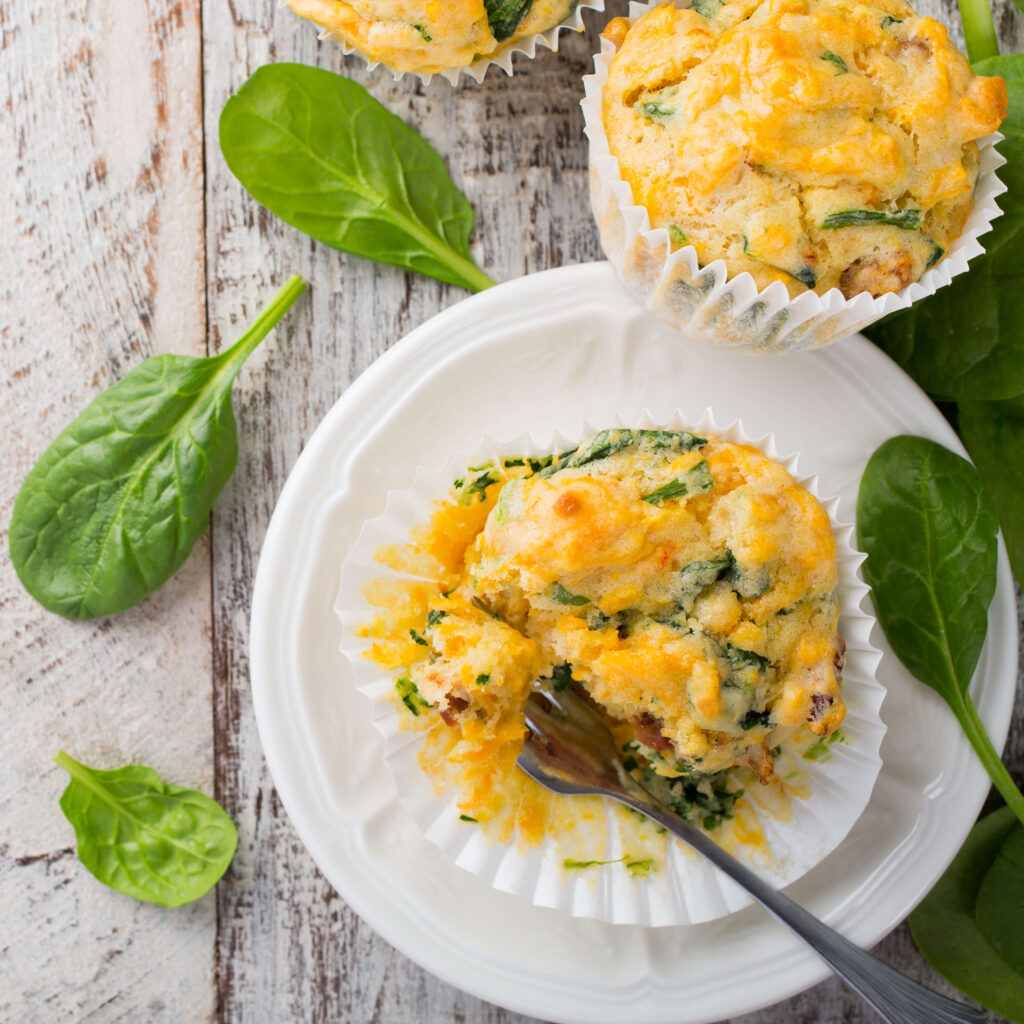Spinach Goat Cheese and Sweet Potato Muffins on a plate with raw spinach